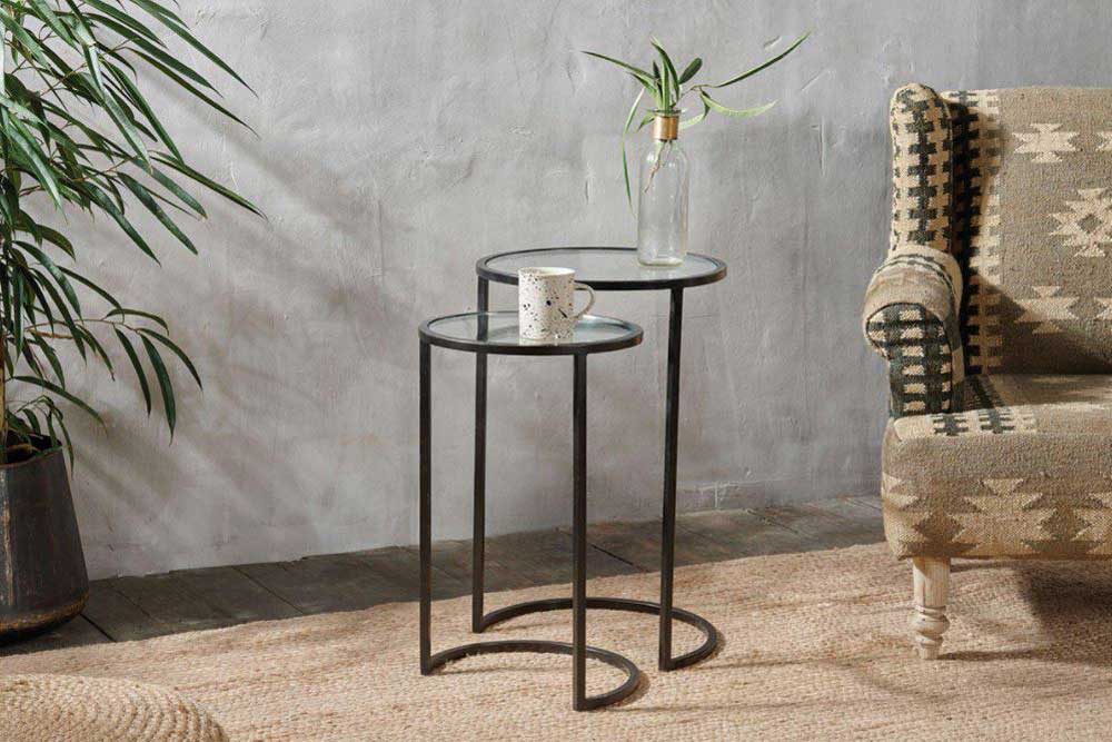Two nested iron and glass side tables